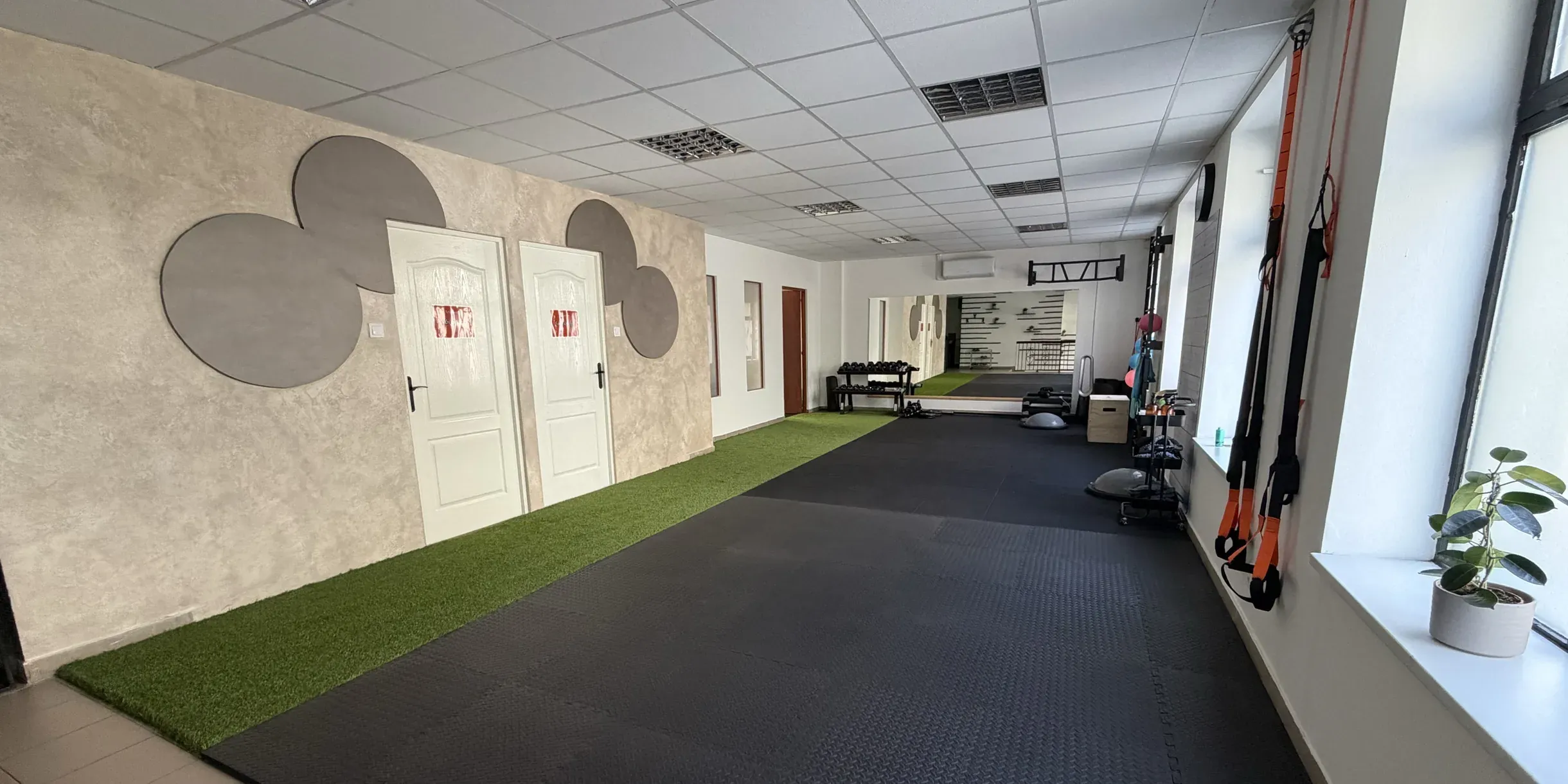 The training area of the Movement Club: an artificial turf lane, rubber flooring, suspension straps and large windows