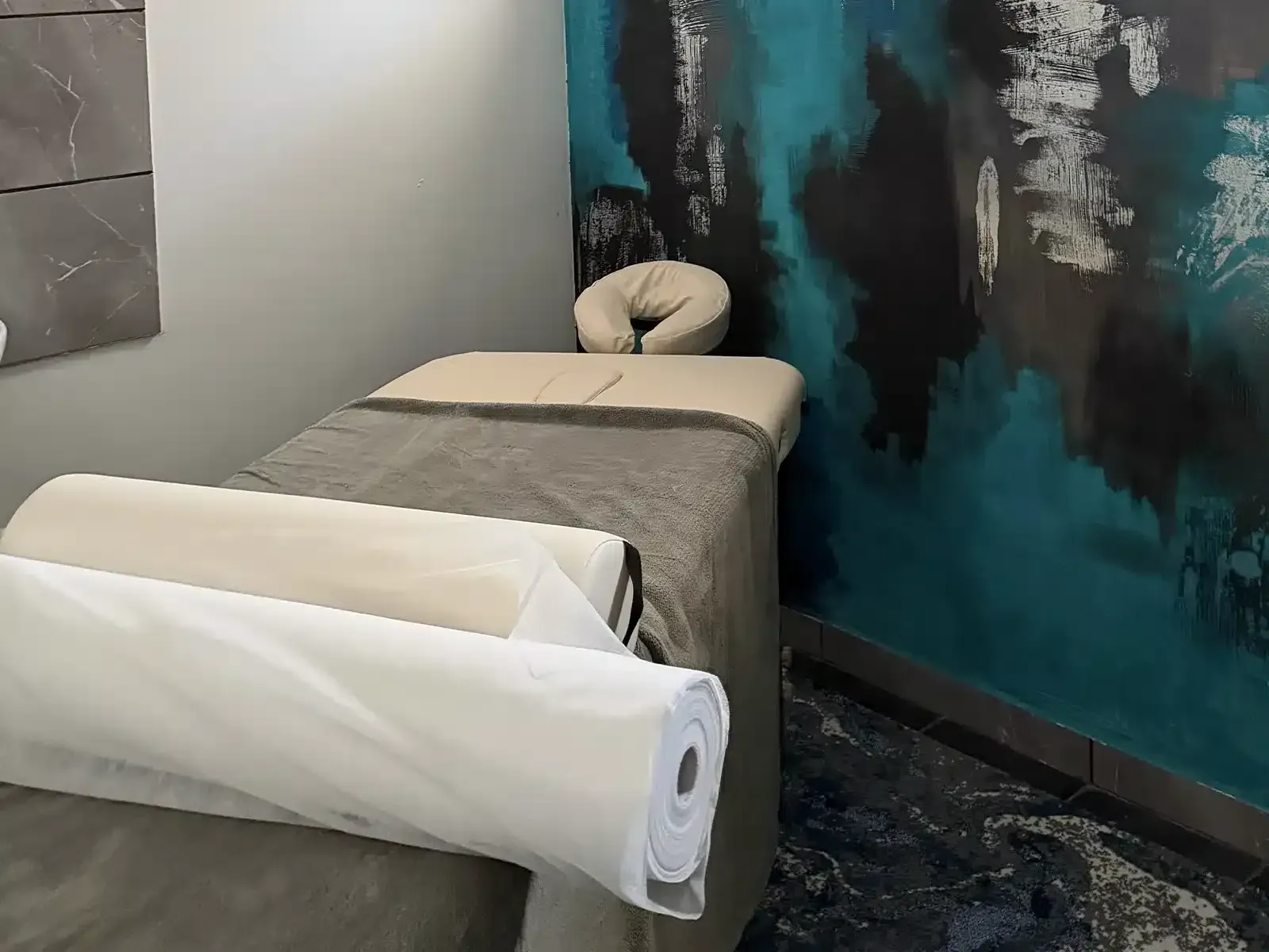 Massage room at the Movement Club: treatment table with a face rest, in front of a teal and grey painted wall
